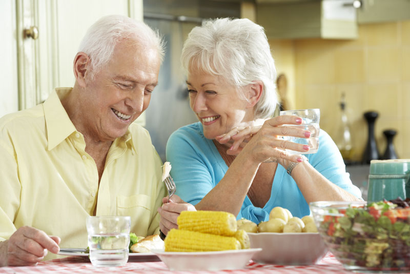 Dental Implant Patients Smiling And Eating Dinner Together