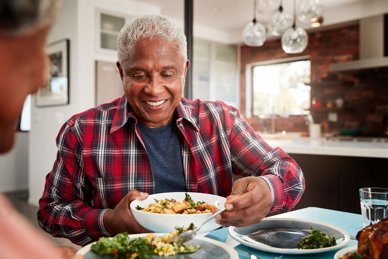 a picture of an all-on-4 dental implant patient smiling while he is eating