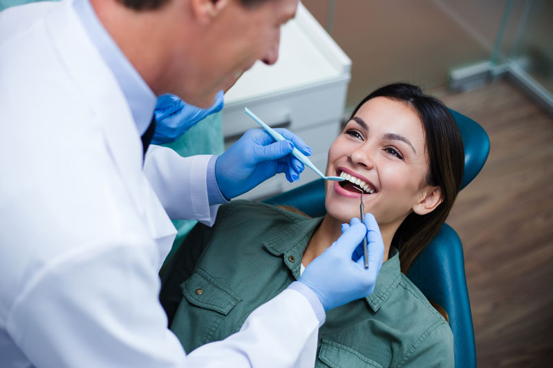 a woman getting a dental exam with a male doctor hovering over her
