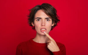 Close-up portrait of gum inflammation. A cropped shot of a young woman showing red bleeding gums isolated on a bright red background. Dentistry, dental care